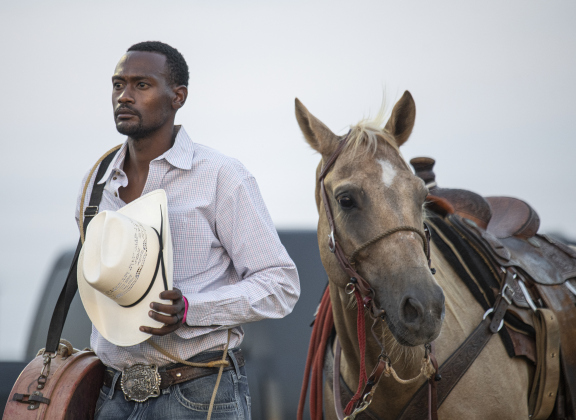 Eddie Dever of Bellville, Texas, competing in Tie Down Roping, stands with his horse Tweetie  during the National Anthem.