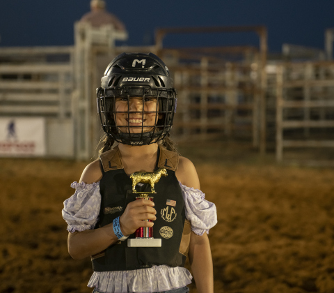 Riata Rafferty holds onto her first place trophy for her win in Mutton Bustin'.