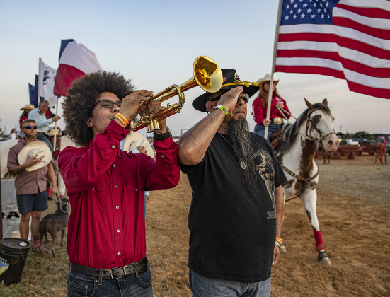 Emilio Garcia, standing with his father, Rick Ramos, plays TAPS as a riderless horse is led through the arena by Scott Gollihare.  The riderless horse honored Joe Hoyle.