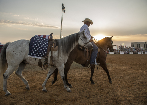 Scott Gollihare enters the arena with a riderless horse honoring Joe Hoyle, plus first responders and members of the military.