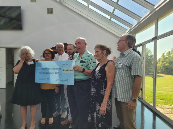 Ed Komandosky, center, presents a $1 million dollar check to Diana Philips, left, wearing black, for the Greater Taylor Foundation’s Impact Taylor initiative.