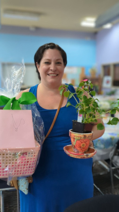 Sara MacDonald holding a decoupage flower pot made at Moms Rising Circle.
