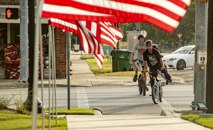 Youngsters enjoy an evening bike ride near American flags at Heritage Square Park on Tuesday, July 4. Photo by Andy Sharp