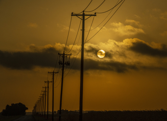 The sun peeks out of clouds over County Road 395 about 20 minutes after sunrise on Saturday, August 12.  Photo by Andy Sharp.