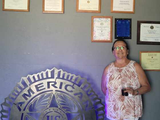 Commander Mary Semek stands next to the Joe Kott American Legion Post 317 sign. It was made by Jarrell High School’s FFA after the Legion donated a scholarship to the program.  Photo by Nalani Nuylan.