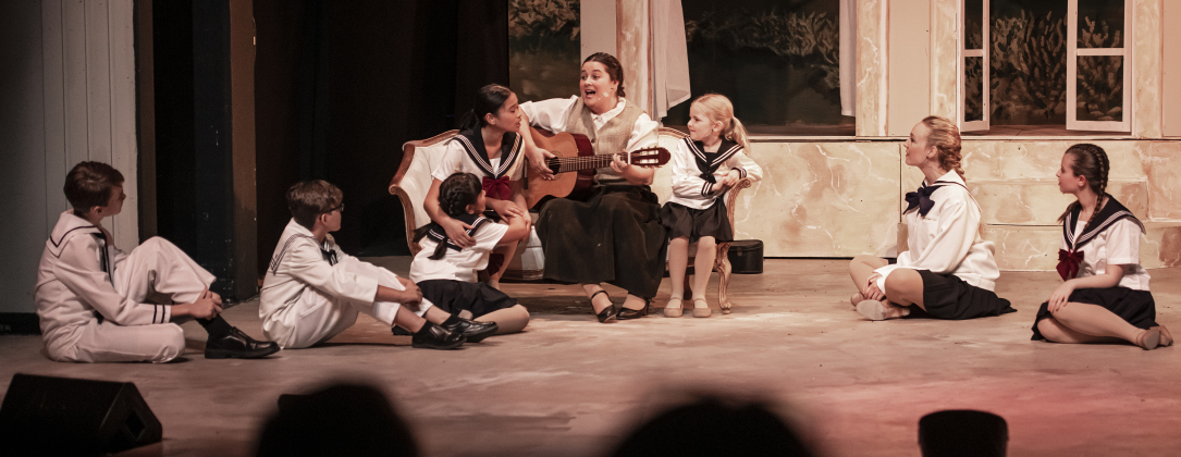 Cassidy Thompson (with guitar)  as Maria Rainer, is pictured with actors playing the Von Trapp children   in a Thursday, August 17, 2023 scene from the Georgetown Palace production of "The Sound of Music," playing on the Springer Stage through September 17.  Photo by Andy Sharp.