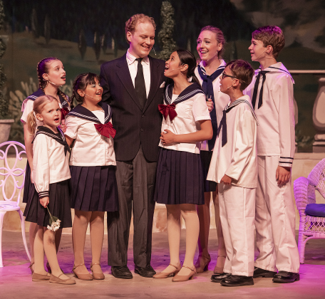 Creighton Moench, as Captain Georg Von Trapp, is pictured with actors playing his children, including (left to right) Ellie Jackson (Gretl), Jordyn Bauer (Brigitta), Coco Taylor-Castro (Marta), Lillian Gabrillo (Louisa) Kelsey Hughen (Liesl), William Reeves ( Kurt) and Sean Condon (Friedrich)  in a Thursday, August 17, 2023 scene from the Georgetown Palace production of "The Sound of Music," playing on the Springer Stage through September 17.  Photo by Andy Sharp.