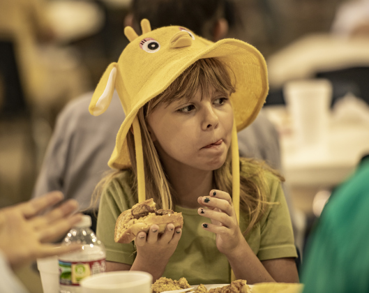 Wearing her duck hat, 10-year-old Melynnie Sladecek enjoys her lunch.