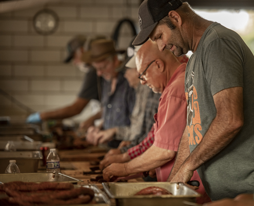 Marvin Vrana joins others cutting brisket and sausage  in the smoking pit area.