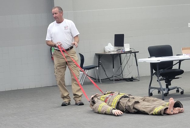 Inventor Charles Ashby explains the improved Hands-Free Extractor at the Jarrell ISD Cafeteria Annex Building on October 11. The invention can be attached at the hips, slung across the shoulder or pulled. Photo by Nalani Nuylan.
