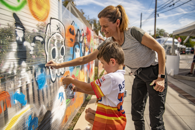 Inga Conway helps her son Fin, 5, use spray paint to create a mural at the South Main Arts Festival on Saturday, October 21, 2023.  Attendees were encouraged to add their own splashes of spray paint color.