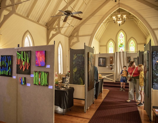 Jennifer Lake, with her son Andrew, 7, and  daughter Adeline, 9, looks at the art created by Sonia Colonna Mathis and her  other family members for the  7th Annual Haunted Art House exhibit inside Grace Heritage Center during the South Main Arts Festival on Saturday, October 21, 2023.