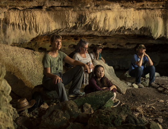 Katharine Beisner, left, joins other attendees as they explore one of the limestone caves at Pecan Springs Karst Preserve on Saturday, September 23, 2023.