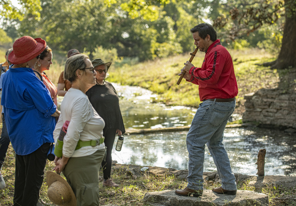 Dr. Aaron Pyle, a board member with the Indigenous Cultures Institute in San Marcos, plays a flute as attendees gather for a land blessing.