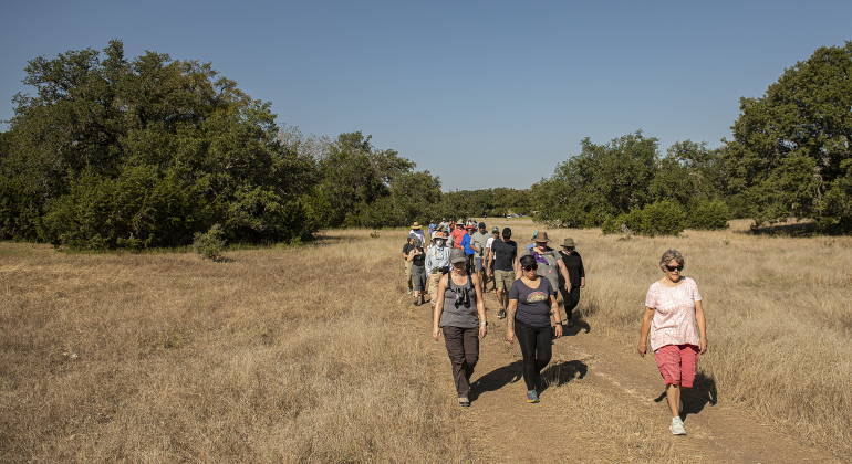 Attendees hike through one of the expansive fields of grass at Pecan Springs Karst Preserve on Saturday, September 23, 2023.