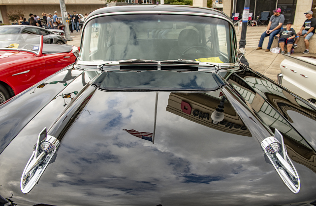 The hood of a 1957 Chevrolet 210 owned by Terry Tschoerner reflects an American flag and sky along Main Street  at  Taylor's Main Street Car Show on Saturday, October 28, 2023.