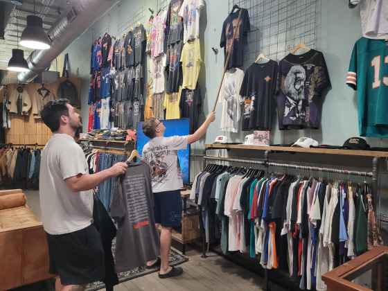 Jay Revord, left, and Jesse Greatting, right, arrange the vintage t-shirt collection on the walls of their shop. The duo got the store in 2022.  Photo by Nalani Nuylan.