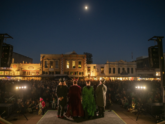 The Uptown Carolers sing from the courthouse steps under a Waxing Gibbous moon (94% visibility) during the Lighting of the Square on Friday, November 24, 2023.  A huge crowd filled all the streets around the square for the annual event.