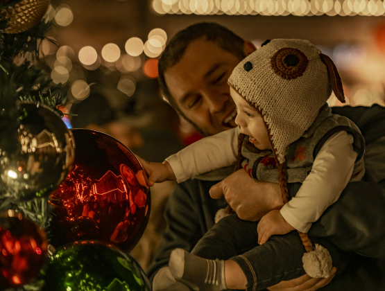 6-month-old Mason Jobe, touching an ornament on the Christmas tree, enjoys his first Christmas with his father Tanner Jobe during  the Lighting of the Square on Friday, November 24, 2023.