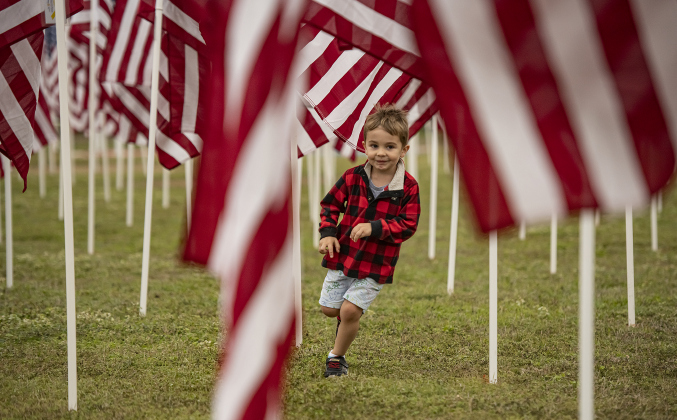 4-year-old Boone Coffey enjoys running through a sea of  American flags at the Field of Honor on Saturday, November 4, 2023.
