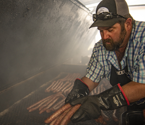 Kyle Kokel helps with sausages in one of the smoking pits during the 51st Annual Wurstbraten at Zion Lutheran Church on Monday, November 6, 2023.