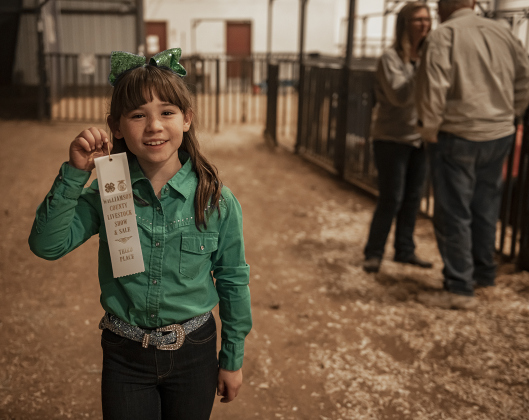 8-year-old Reagan Erickson of Georgetown, a member of the Williamson County 4-H Club, holds up the third-place ribbon she won while showing her pig named Dottie  during the Williamson County Livestock Show on Tuesday, December 5, 2023.  This was Reagan's first time to take part in a livestock show.