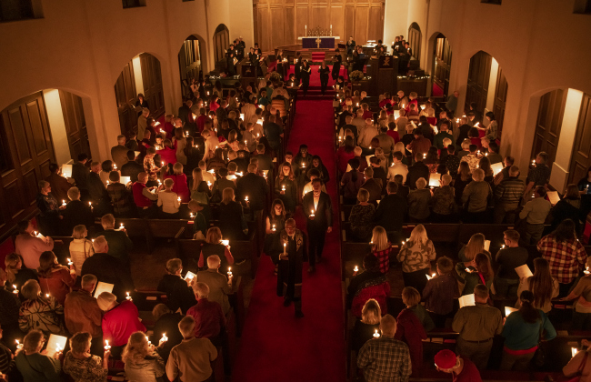 Rev. Dr. Ronald Swain, the school's chaplain, leads a recessional through the aisles  during Southwestern University's Candlelight Service at Lois Perkins Chapel on Thursday, December 7, 2023. Attendees gathered outside the chapel, singing "Silent Night" to conclude the service.