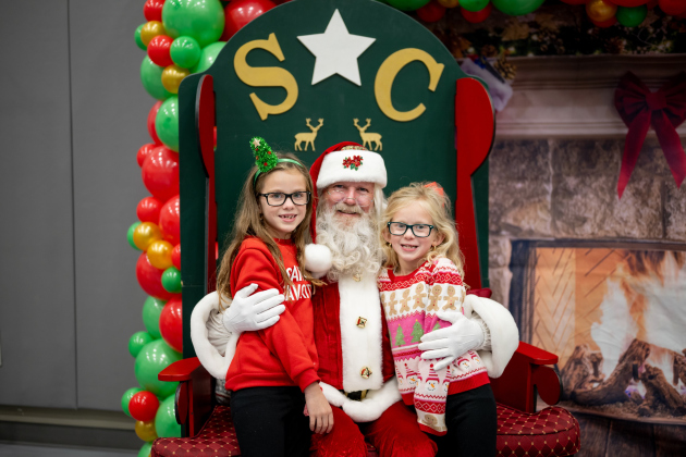 Reagan and Tatum Hauser have taken pictures with Charles Guillote as Santa Charles for four years.  (Photo courtesy Sarah Saiz)