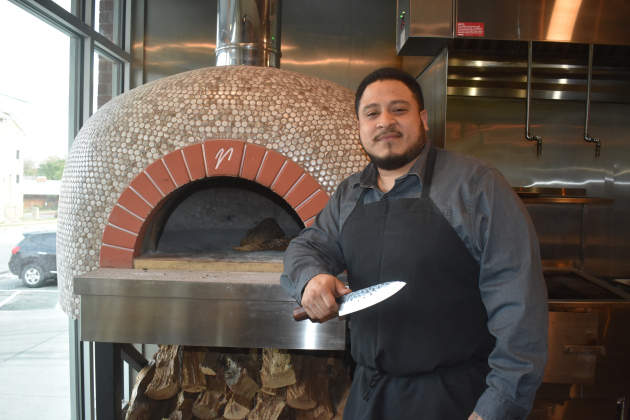 La Riv Executive Chef Johnny Pincay, with his favorite chef’s knife, at the restaurant’s wood-fired pizza oven. The oven uses three cords of wood weekly.