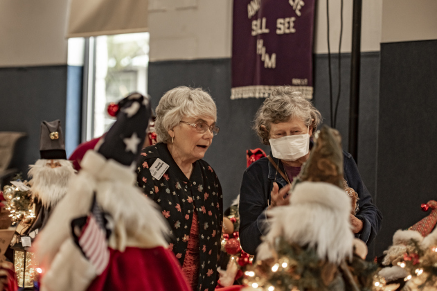 Beverly Thompson, left, and Billye Adams, right, look over Santa Claus creations made by Nancy Crouse, owner of Nancy's Santies, during the Come Home for Christmas Celebration at St. John's Methodist Church on Saturday, November 18.