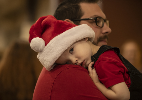 2-year-old Leeland Westberry rests on the shoulder of David Westberry, his father, as they wait in the food serving line together.