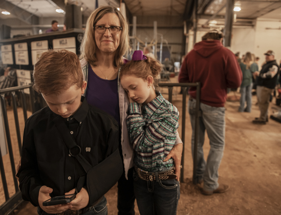 11-year-old Timothy Blume, left, and his sister, Abigail Blume, 9, right, members of the Thrall 4-H Club, are show with their grandmother Anne Giddings during the Market Rabbit Show at the Williamson Livestock Show  on Sunday, December 3, 2023.  Abigail is resting on grandma's shoulder after just completing her time in the show arena.   Both kids participated in the Market Rabbit Show even though Timothy has a broken collar bone.