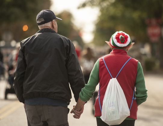 Betty White, wearing her elf ears, walks along Main Street with her husband Tom White.