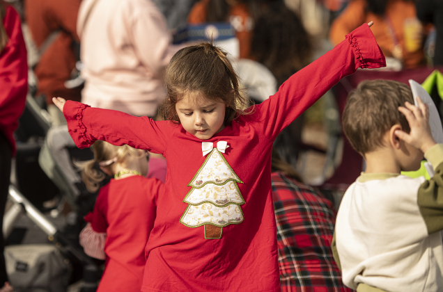4-year-old Lillian Pickel gets into the dance spirit as she waits with her family for the parade to come along Austin Avenue.