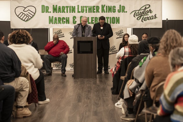 Pastor George Qualley, standing at left, Senior Pastor at St. Paul Evangelical Lutheran Church, and Rev. Dr. Anthony L. Watson, Sr., standing at right, pastor at The First Baptist Church of Taylor, offer a prayer during Taylor's Dr. Martin Luther King, Jr. holiday observance held in the Taylor City Hall auditorium.
