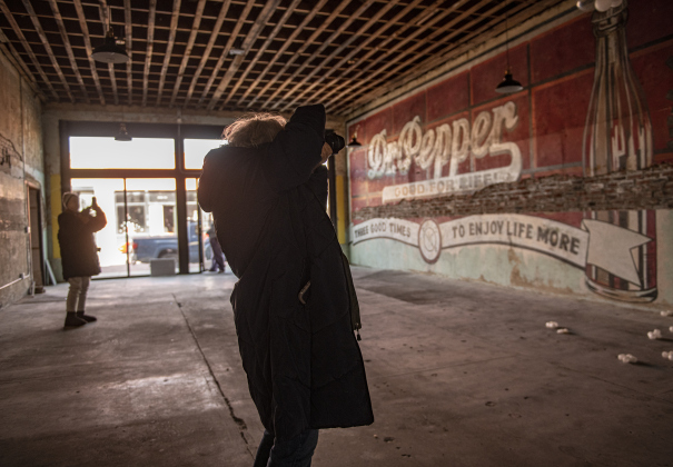 Photographers Raena Wharton, front, and Winifred Simon, back left, take photo of a restored Dr. Pepper mural inside an  historic Bartlett building along East Clark Street.