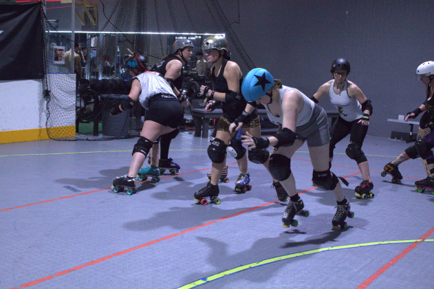 Meghan Sammons, who goes by Goldie when playing roller derby, wears a blue helmet covering called a pantie and skates through the blockade. Photo by Nalani Nuylan.