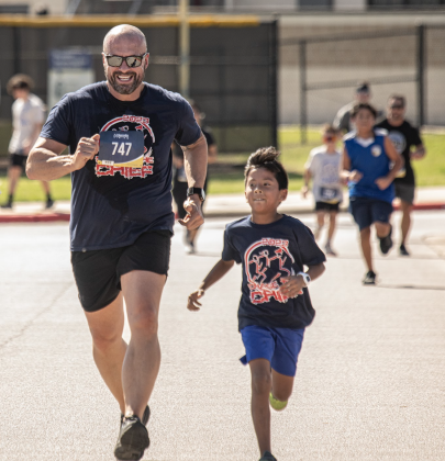 Georgetown Police Chief Cory Tchida, left, is joined by 8-year-old Ellison Shotwell as they near the finish line for their 5-K Race during Chase the Chief, held at East View High School on Sunday, March 5, 2023. Chief Tchida ran in both races. 