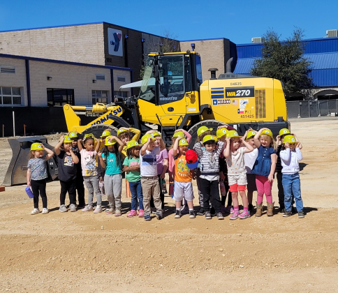 Children from the Chasco Family YMCA Early Childhood Center pose in front of a bulldozer before the groundbreaking ceremony.  Photo by Nalani Nuylan.