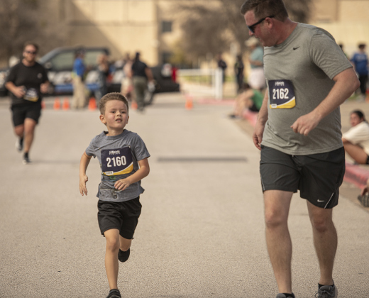 6-year-old Austin Fleming, left, gets encouragement from his dad Brian Fleming, right, as they near the finish line together in the 5K race.