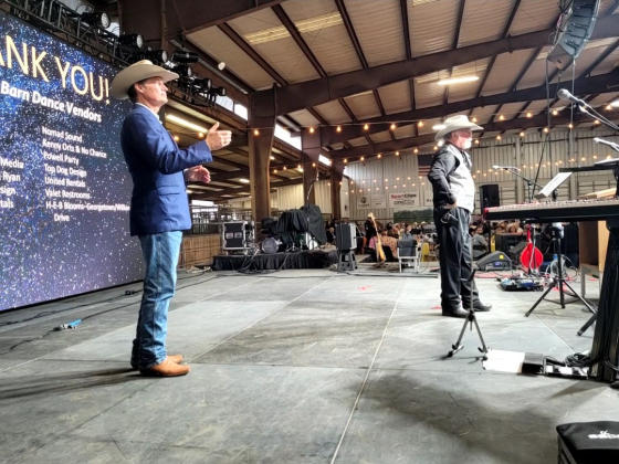 Emcee Dan Gattis, left, flips a coin while Auctioneer Patrick “Doc” Breen, right, waits to announce if it lands on heads or tails as part of a game.