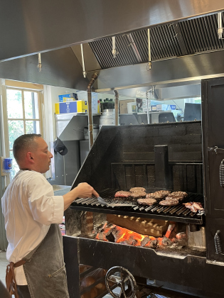 Chef Adi flips Wagyu Burgers on open-flame woodfire grill.