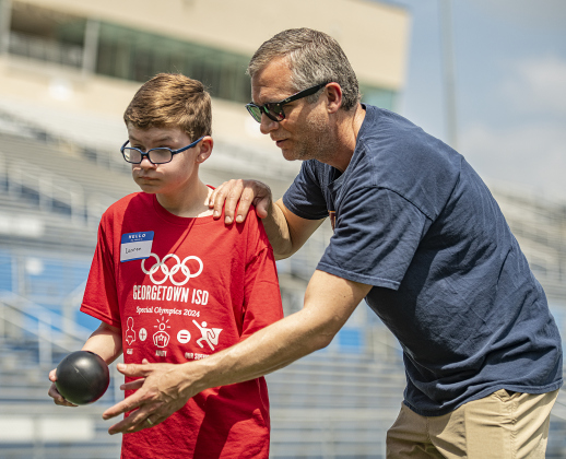 14-year-old Cannon Collier, left, a student at Tippit Middle School, gets guidance from his dad Brandon Collier in a bowling event during  the Georgetown Independent School District's annual Special Olympics, held Tuesday, May 7, 2024  at the district sports complex behind Georgetown High School.     Photo by Andy Sharp.