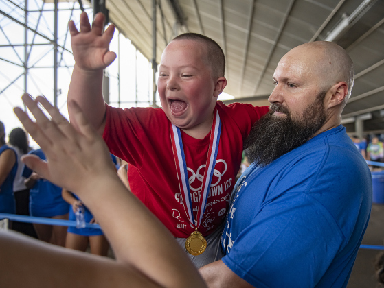 6-year-old Tyler Brandon, a student at McCoy Elementary School, is with games volunteer helper Steven Linyard as he gets high-fives for the medal he won during the Georgetown Independent School District's annual Special Olympics, held Tuesday, May 7, 2024  at the district sports complex behind Georgetown High School.     Photo by Andy Sharp.