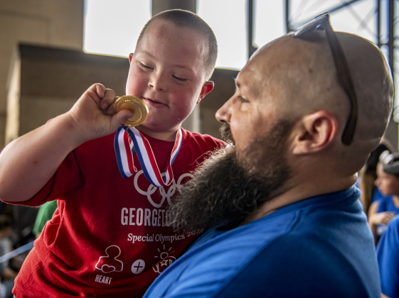 6-year-old Tyler Brandon, a student at McCoy Elementary, is held by games volunteer Steven Linyard as he admires the medal he won during  the Georgetown Independent School District's annual Special Olympics, held Tuesday, May 7, 2024  at the district sports complex behind Georgetown High School.     Photo by Andy Sharp.