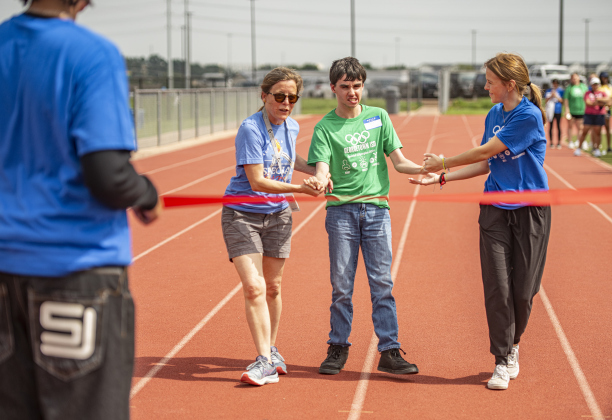 Georgetown High School student Shawn Eisbrenner, competing in a 50-yard track event, is assisted by physical therapist Julie Mani, left, and Georgetown High student Marissa Gephart, right, during  the Georgetown Independent School District's annual Special Olympics, held Tuesday, May 7, 2024  at the district sports complex behind Georgetown High School.     Photo by Andy Sharp.