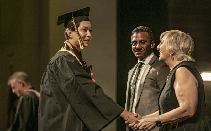 Farzad Azizi accepts congratulations from superintendent Dr. Devin Padavil and GISD Trustee  Stephanie Blanck as he walks across the stage.