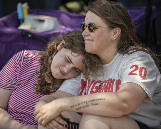 Scout Holzer, left, and her mom Ash Holzer found a shady area to listen to musical performances  during the 4th of July celerbration in San Gabriel Park on Thursday, July 4, 2024.  They live in California, but are in for a family gathering in Austin and Georgetown this week.   The Georgetown Sertoma Club sponsors the 4th of July Freedom Festival each year in San Gabriel Park.  Photo by Andy Sharp.