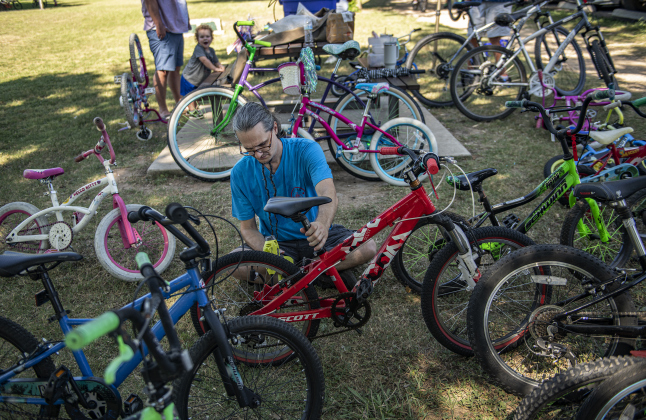 Thomas Holy, a volunteer mechanic with  Georgetown Free Bikes, a non-profit that provides bicycles free of charge to those who need one (www.georgetownfreebikes.org) gets bikes ready for attendees to ride  in the Hometown Parade in San Gabriel Park on Thursday, July 4, 2024.  The Georgetown Sertoma Club sponsors the 4th of July Freedom Festival each year in San Gabriel Park.  Photo by Andy Sharp.