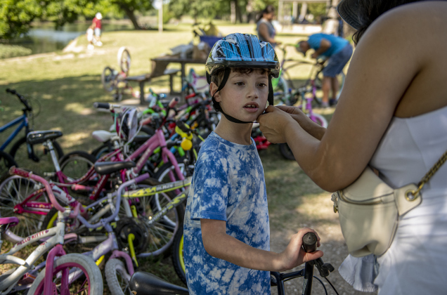 6-year-old Thomas Drobny gets his helmet securely fastened by his mom Myra Castro as he gets ready  to  ride in the Hometown Parade in San Gabriel Park on Thursday, July 4, 2024.  The Georgetown Sertoma Club sponsors the 4th of July Freedom Festival each year in San Gabriel Park.  Photo by Andy Sharp.